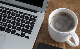 Skrivbord med en laptop och en kopp kaffe